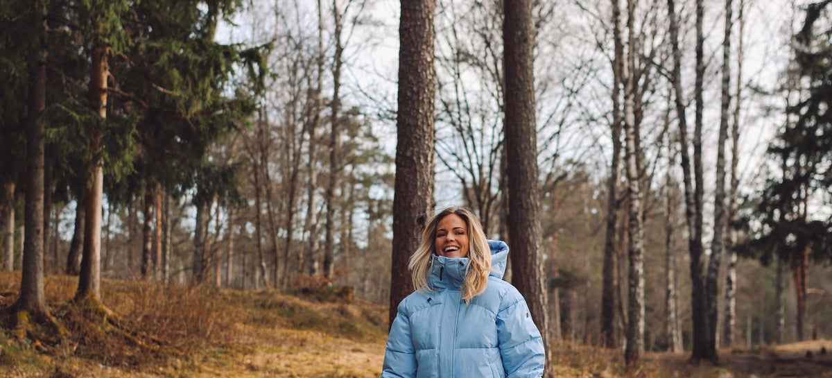 Emilie Nereng i lyseblå dunjakke fra Skogstad i skogen